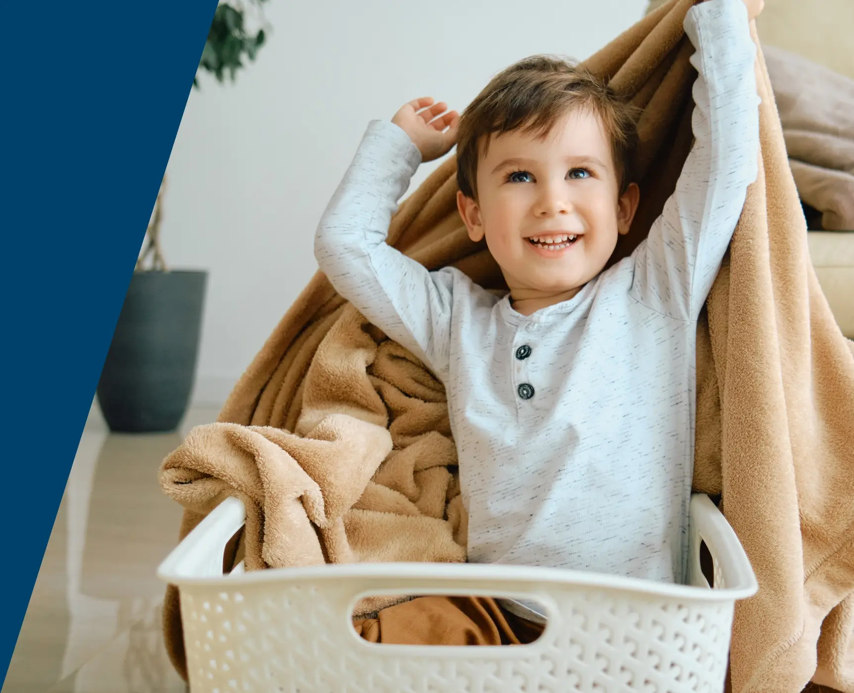 A young child playing in a laundry basket