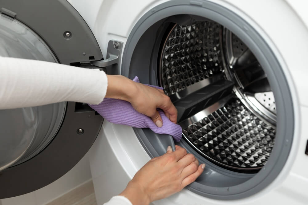 Washing machine being cleaned with cloth